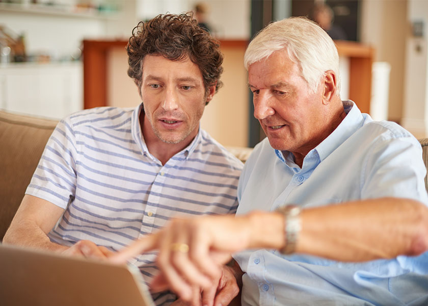A man and his father sitting with a laptop, looking at financial statements